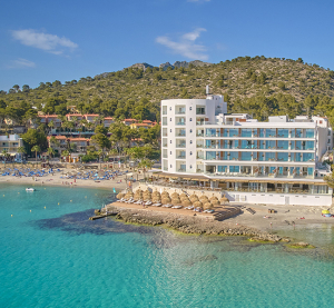 Modernes Strandhotel mit direktem Zugang zum türkisblauen Meer und Sonnenschirmen am Sandstrand.